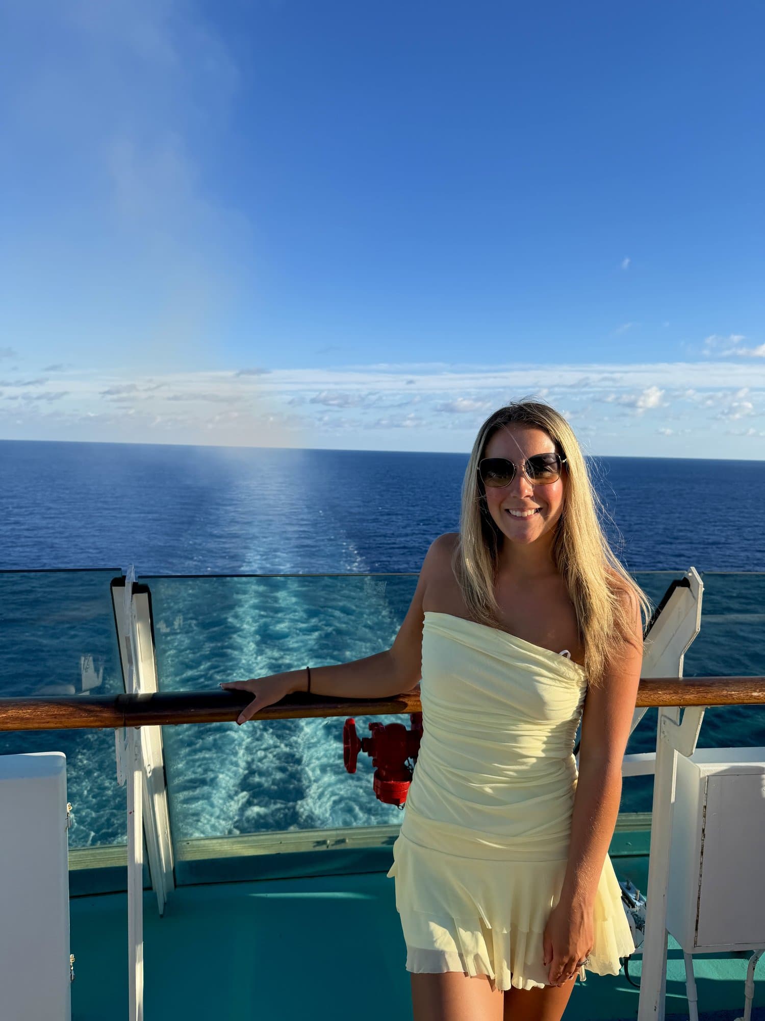 Katrina on the deck of a ship in a pale yellow dress, with a dashed box marking where the sponsor's name or logo would go
